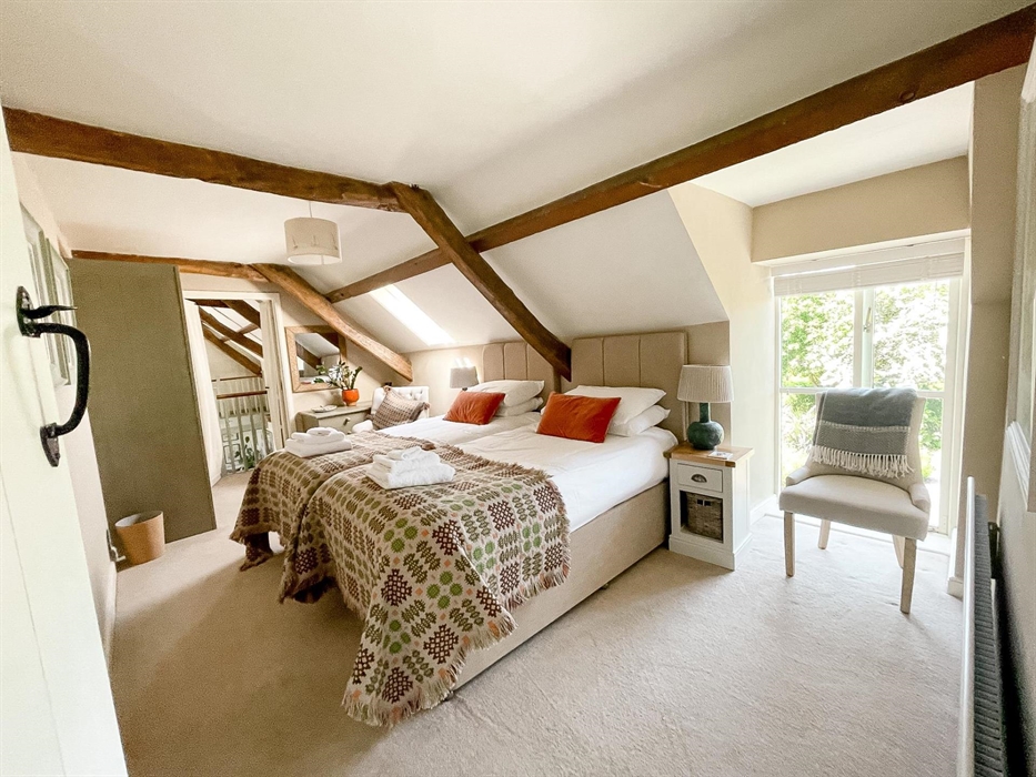 Twin beds in the east wing bedroom at the seadog and stone self catering holiday let ysgubor degwm. Welsh blankets in brown and green with orange thro