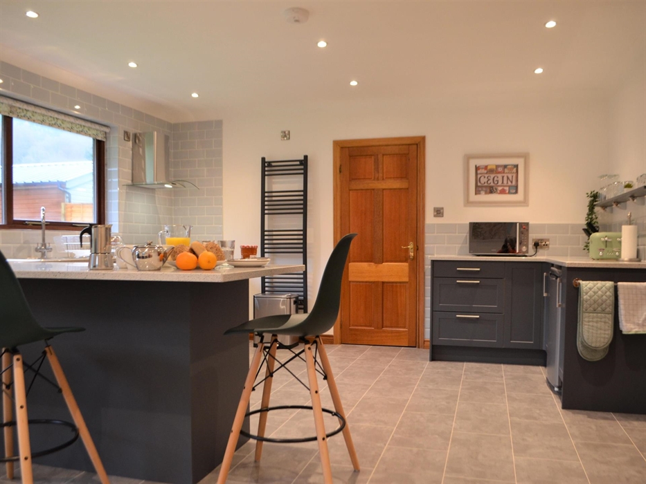 Kitchen with green units and breakfast bar