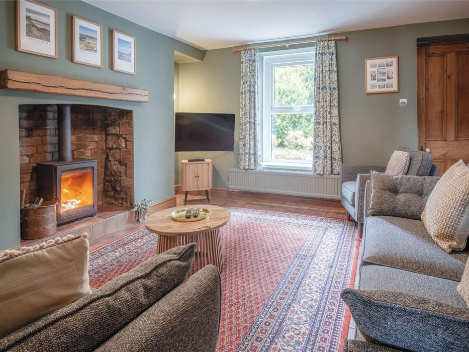 Sitting room with log burner, smart TV and seating for eight. Access to Kitchen, Cinema Room and South facing garden and first floor.