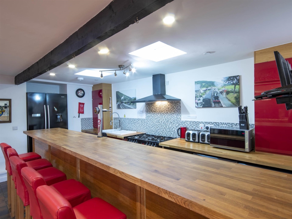 Welsh Row House long breakfast Bar and red leather bar stools. American Style Fridge Freezer. Range cooker with extractor.  Wrexham lager pump on the