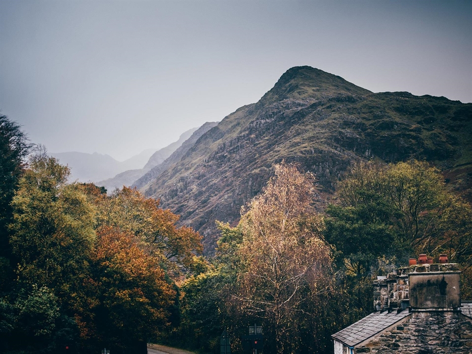 The picture is dominated by the large mountains of Snowdonia. In the foreground, you can see the chimneys of the cottages on site at the museum