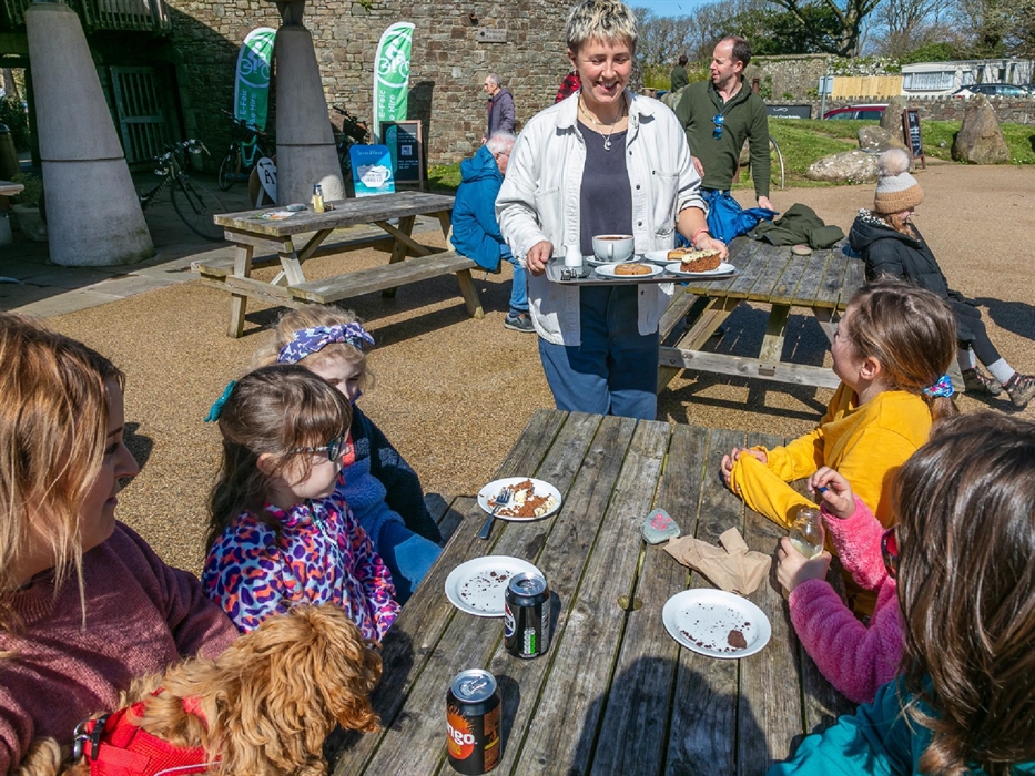 Family enjoying their cakes outside on picnic bench.