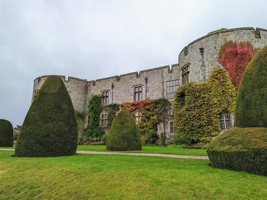 The East Front of Chirk Castle from the gardens, showing autumn colour in the leaves of the climbing plants on the castle walls and yew topiary in the
