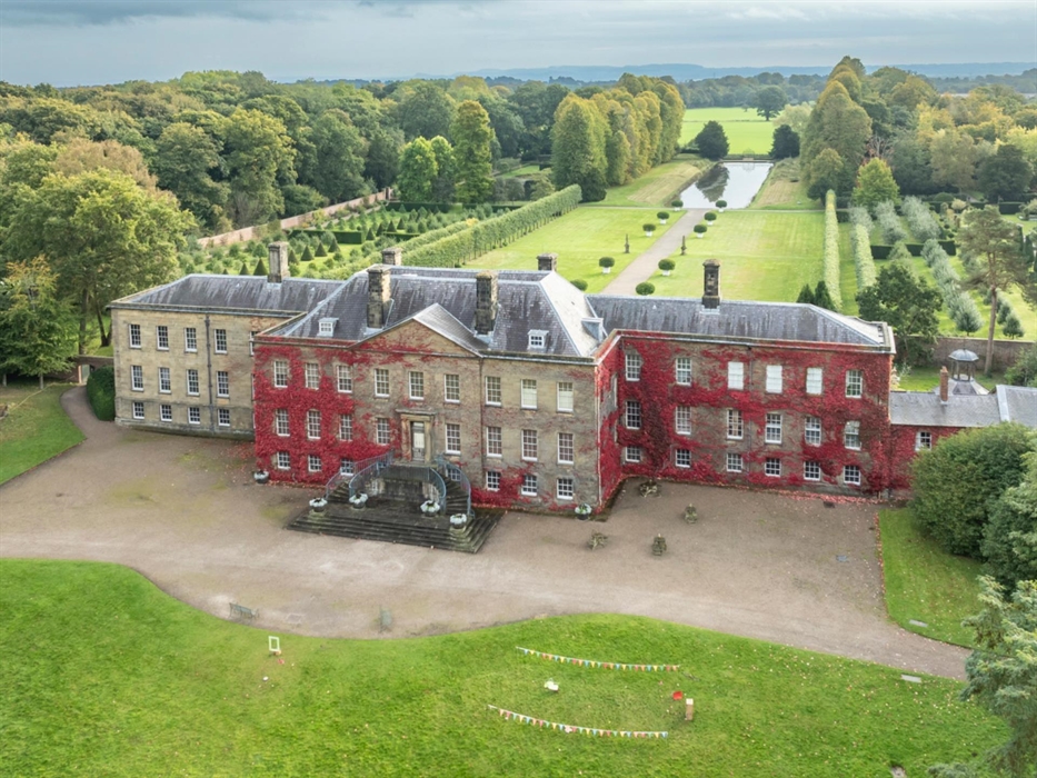 An aerial view of Erddig Hall and Garden in autumn as the Boston Ivy on the exterior walls of the hall turns from green to crimson red.