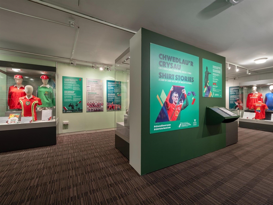 Display cases with vintage Welsh football shirts in Wrexham Museum's gallery.