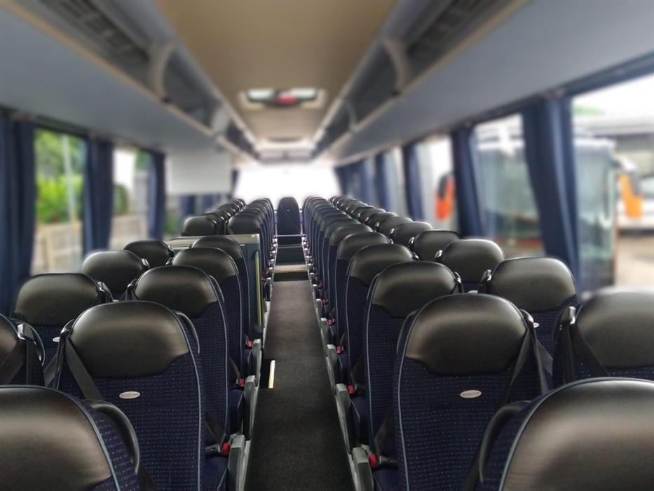 Executive coach interior of Neoplan Tourliner with blue upholstery and black leather headrests. Seats with three-point seatbelts, armrests, footrests