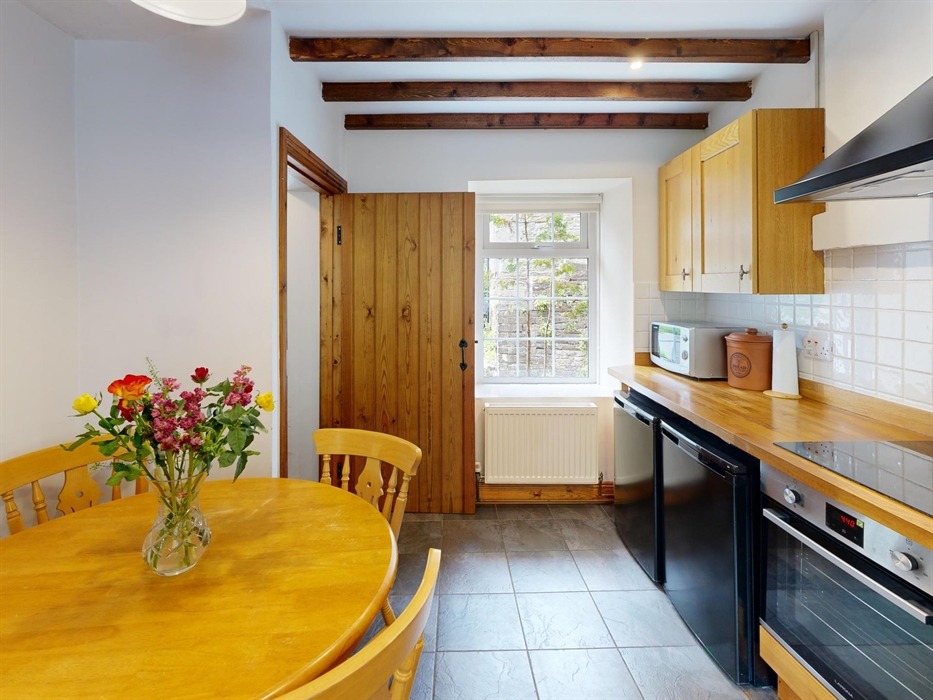 Wooden dining table with flower arrangement set within a rustic kitchen.