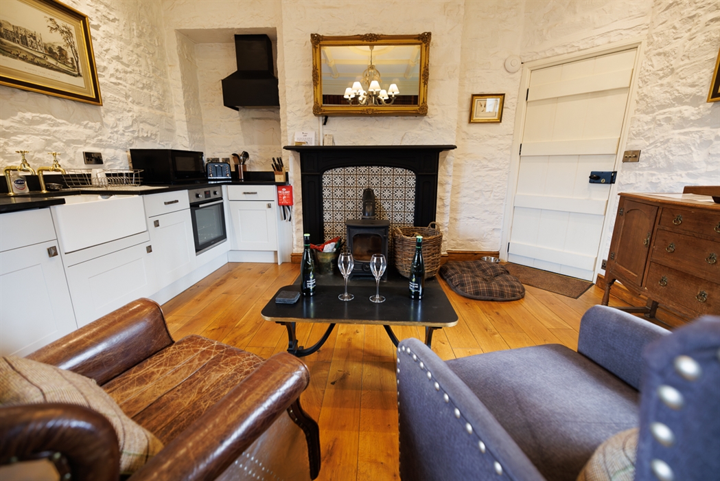 inside the Tower bridge accommodation.  shows two arm chairs with a lovely kitchen and two glasses of wine