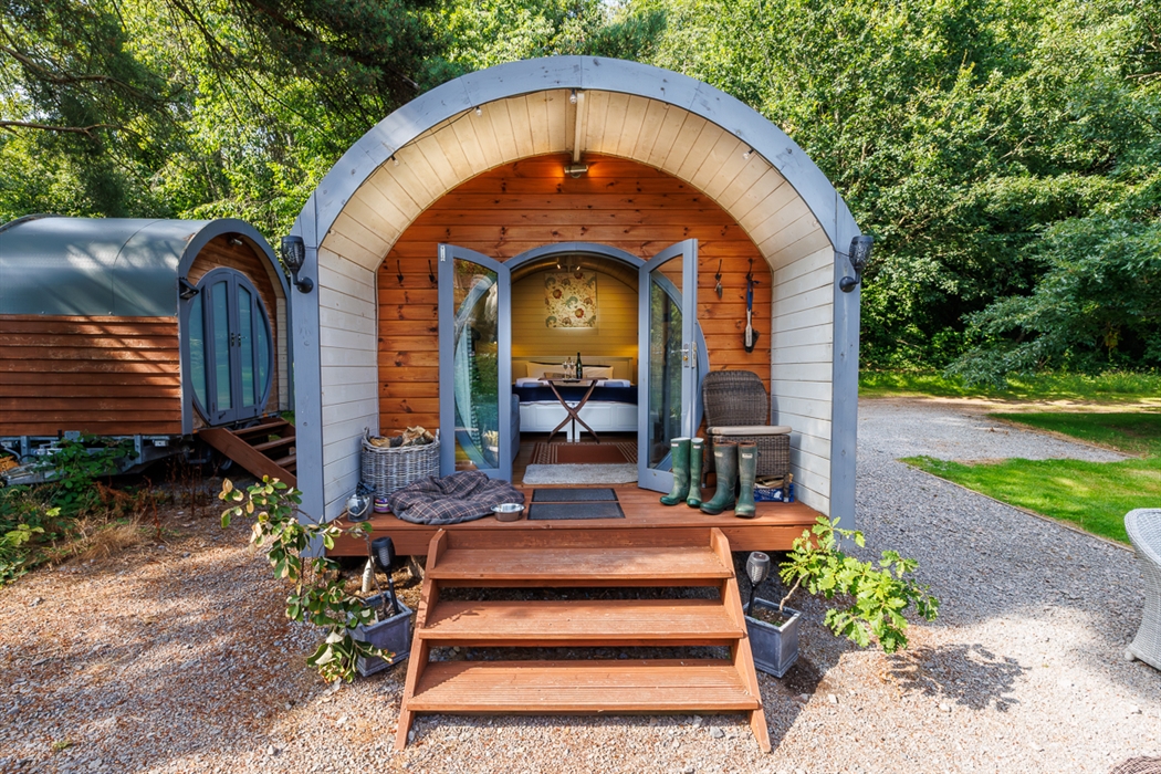 image of The Oak retreat which is situated near the River Usk.  photo shows the 4 steps up to the pod with wellie boots and a dog bed placed just outs