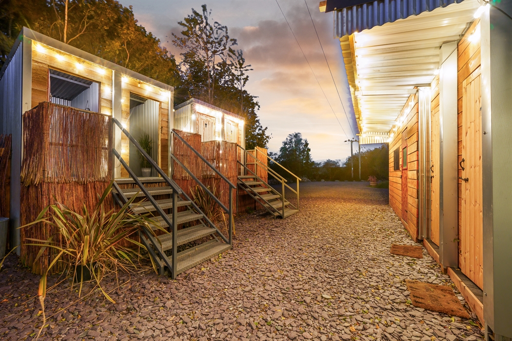 Rustic stylish compost toilets and eco washing facilities, festoon lights in twilight
