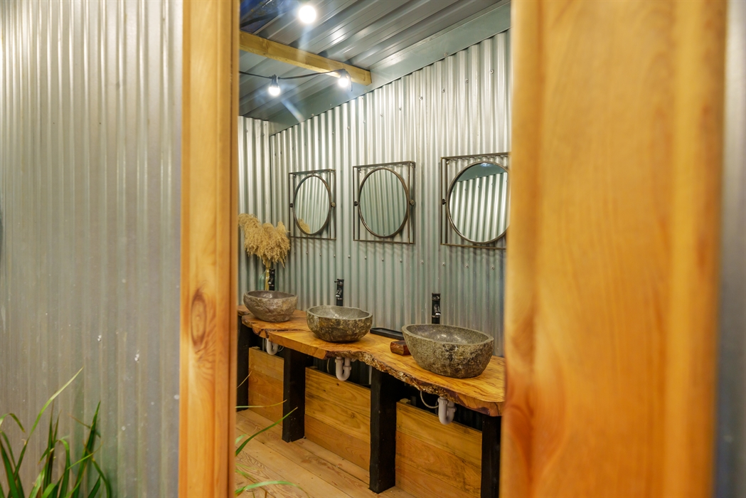 Rustic-style washroom with three granite basins and mirrors