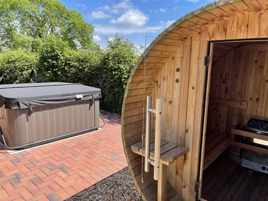 Shows the private garden at the rear of Blackthorn Lodge. It offers a Red Cedar Barrel Sauna, a Jacuzzi, garden table and 4 chairs and lockable outdoo