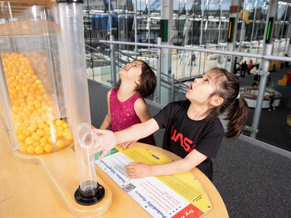 Two children look up at the Probability Pattern exhibit in amazement.