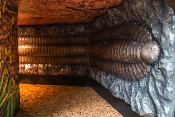 A giant fossil replica of Arthropleura emerging from a tunnel at Plantasia Tropical Zoo