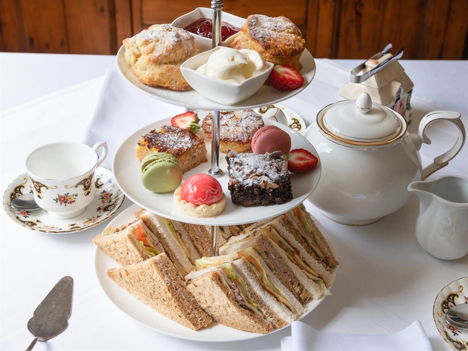 Indulge in a homemade ​luxury afternoon tea, featuring freshly baked scones with ​whipped cream and strawberry jam, ​delectable sandwiches​ and an ass