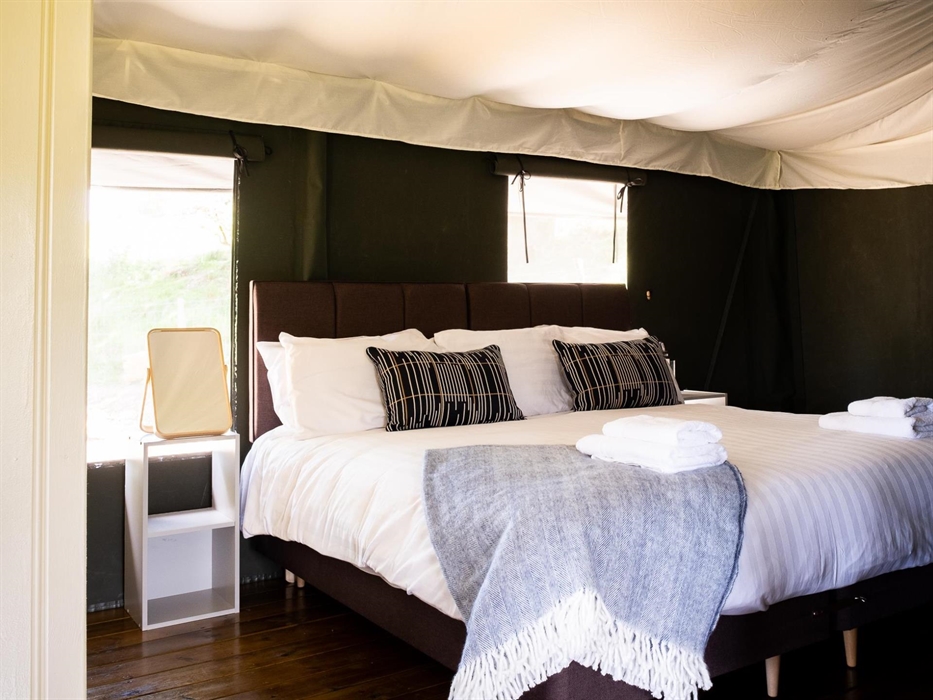 A superking bed made up with white linen and blue blankets and cushions
