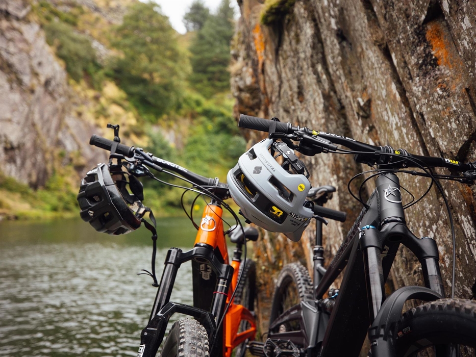 Two electric mountain bikes with helmets hanging off the handlebars.