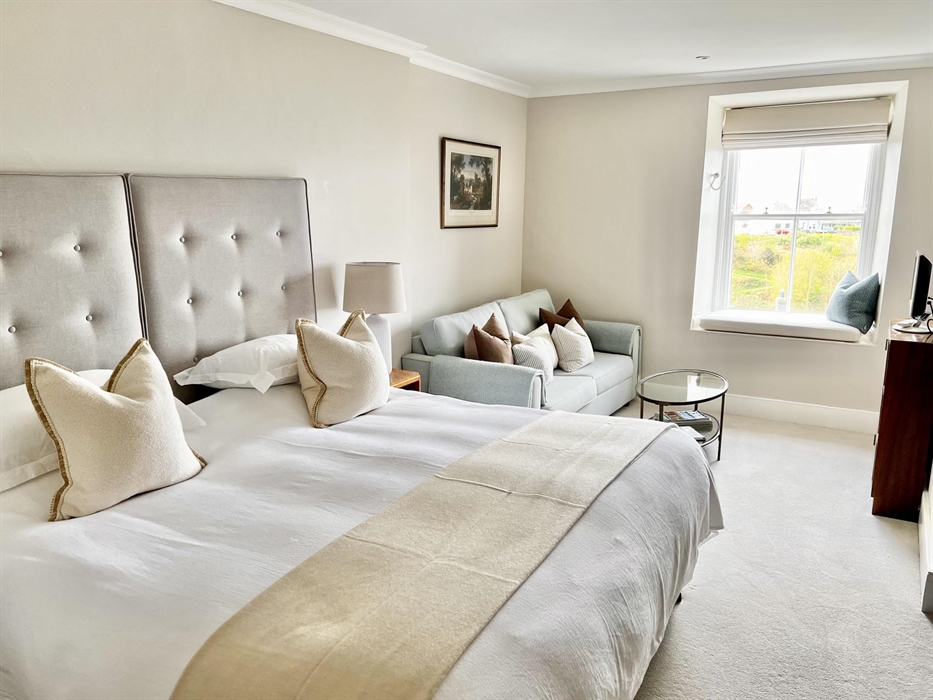 Large bedroom in natural colour scheme, with a window seat overlooking the garden and views across the Irish Sea from Cardigan Bay. The bedroom has Ar