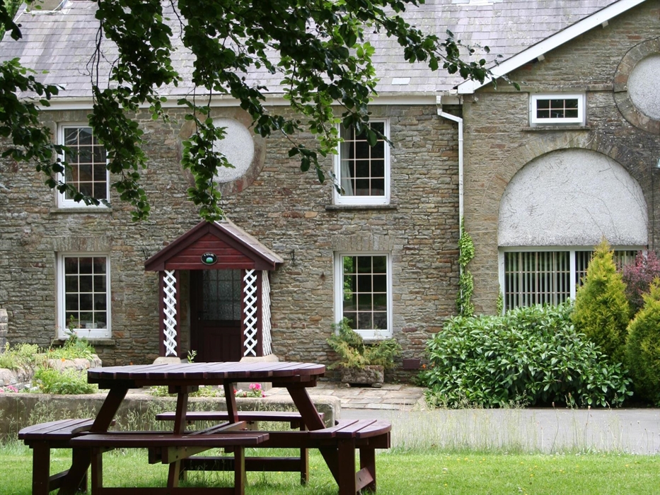 Holiday cottage in Wales that is one half of a Georgian coach house. Lawn and picnic table on lawn in foreground.