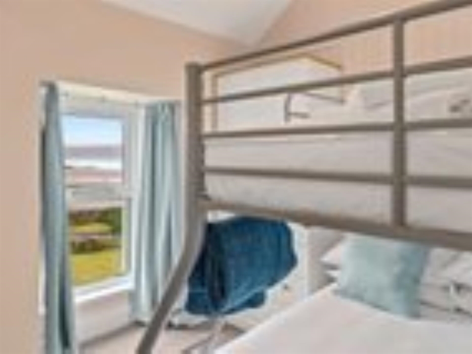 A photograph of the bunk bedroom in apartment 2 showing the beds made up and the view to the beach across the garden