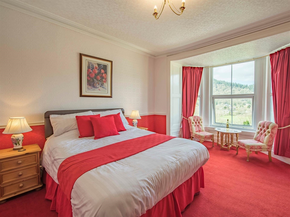 King size room with views overlooking Betws-y-Coed. Window seating area with table room is red and white. Bryn Bella Guest house