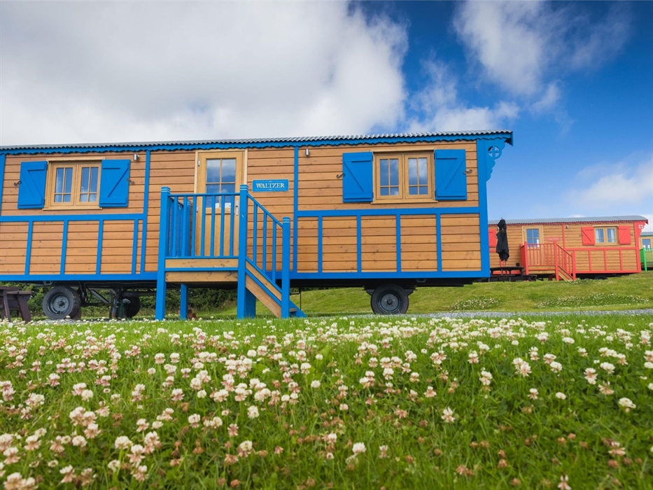 Photo of three brightly coloured vintage style Showman's Wagons