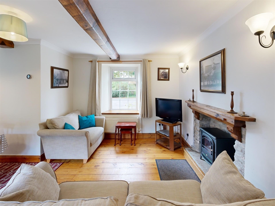 A character-filled lounge featuring exposed beams, a traditional stone fireplace with electric stove, and a family dining area in a cosy corner. Court