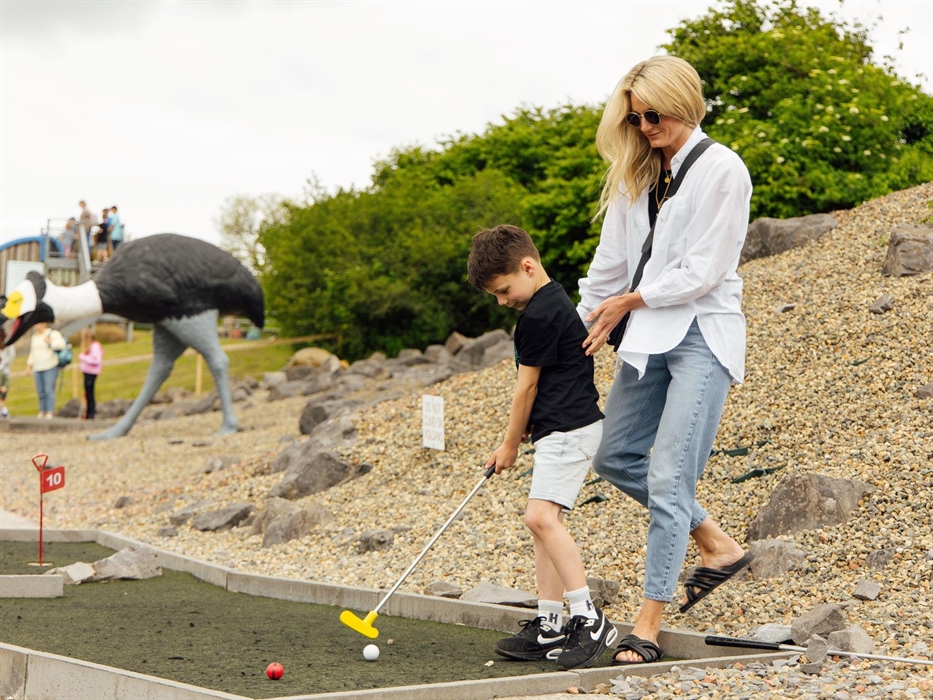 Dinosaur themed mini-golf with a mother and child playing golf