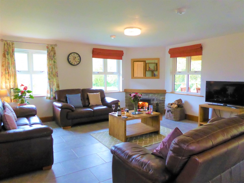 The spacious lounge has 3 comfy leather sofas, there is a log burning stove and a smart TV.  There are also books and games stored in the lounge for e