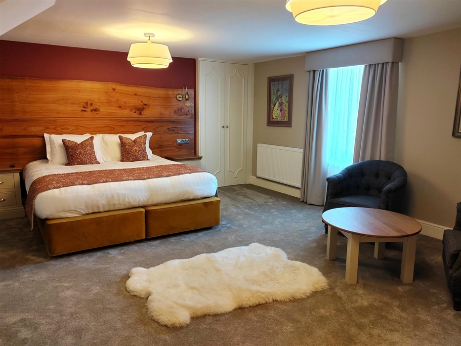 Extra large super king name inspired by Welsh Valentine. Spacious room with large extra large super king bed, armchairs and white furry rug.