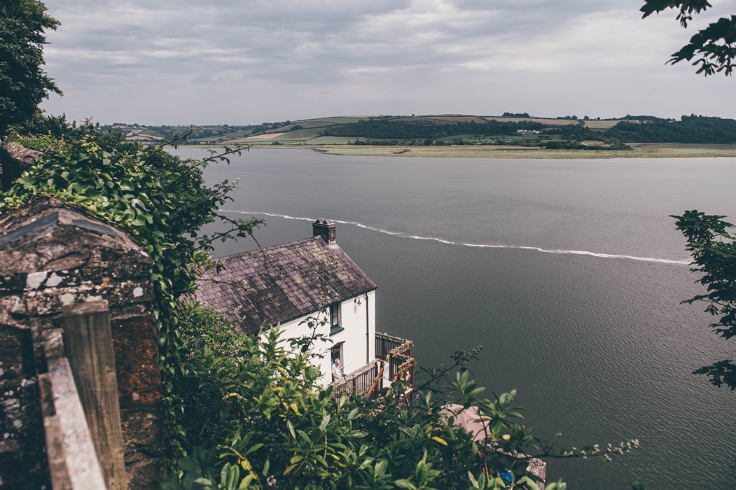 Looking down at the Boathouse from the coastal path. The River Taf occupies the middle ground and a low hill is in the background beyond.