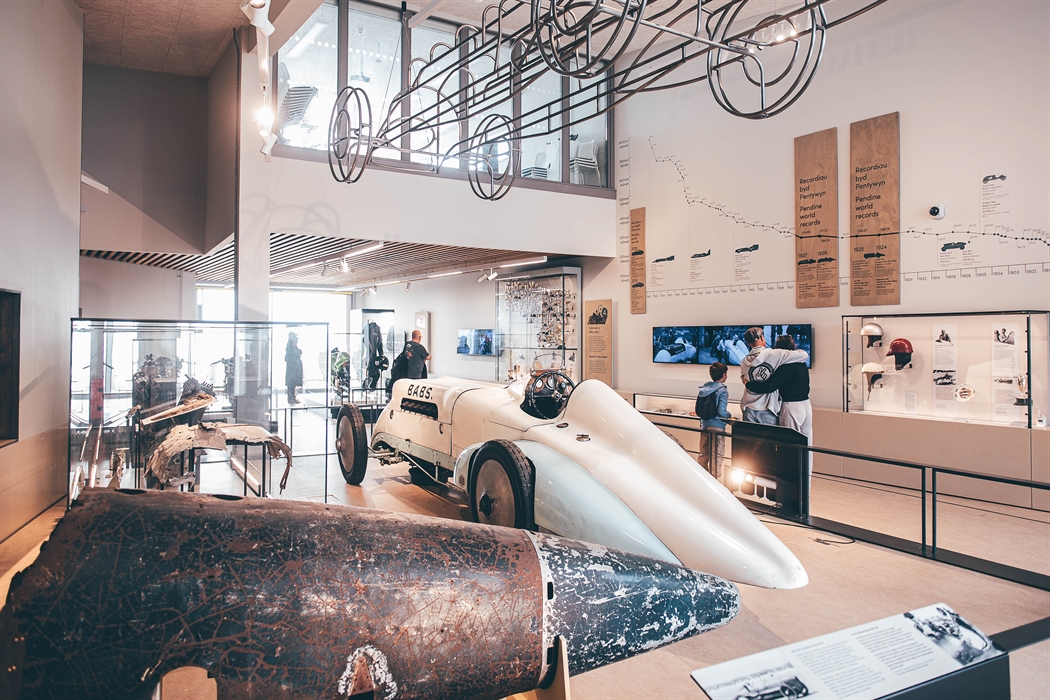Wide angle view of the main museum gallery. A metal tail from the Bluebird car is in the foreground, with the Babs car in the middle ground. A steel f