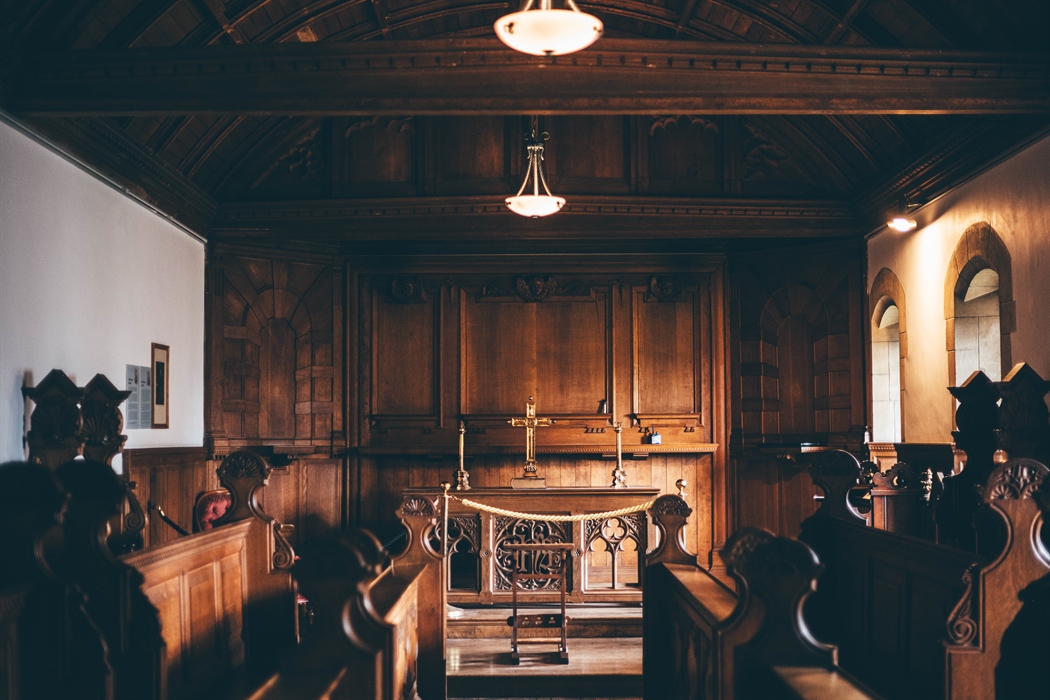 Interior of a wood panelled chapel. Altar at the far end with stalls facing the aisle in the foreground.