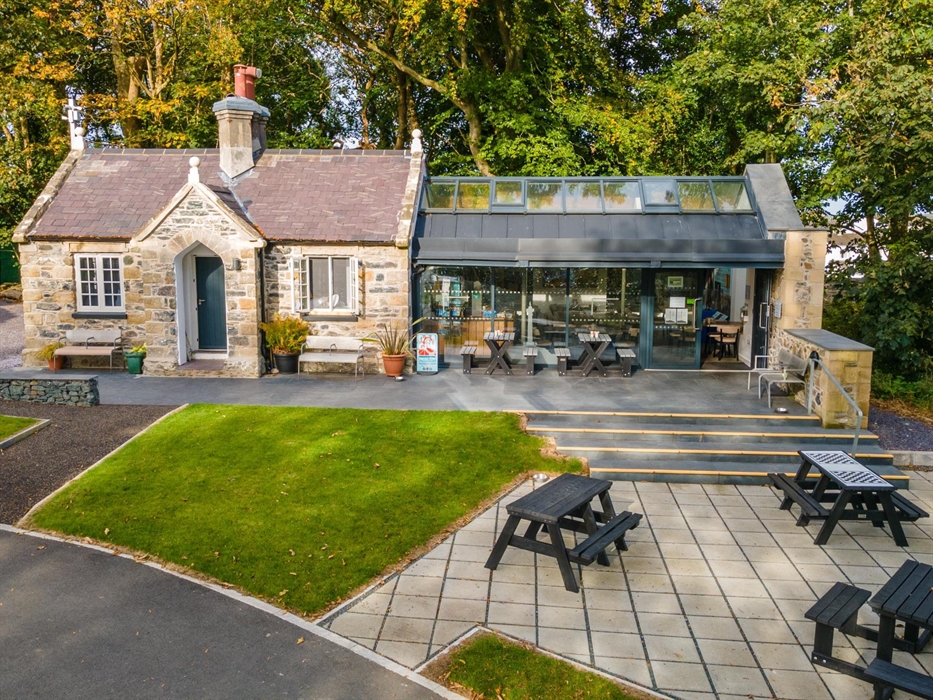 Anglesey Column visitor centre and café with outdoor seating, welcoming entrance, and surrounding greenery on a bright day