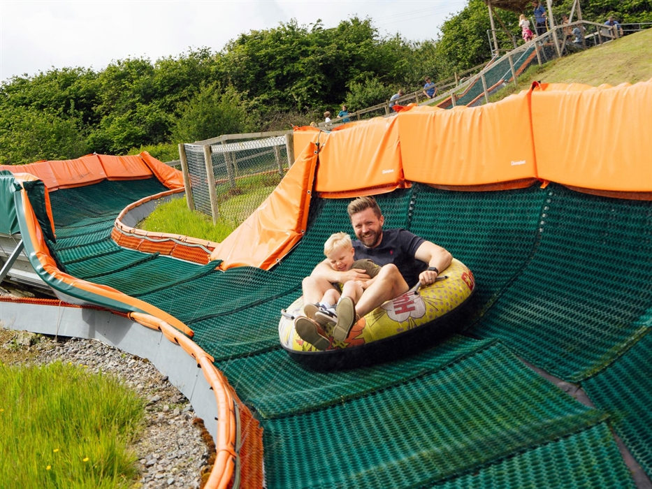 A father and son laughing in the tube as the ride finishes.