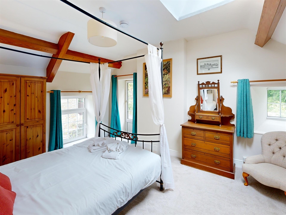 Bright master bedroom featuring a four-poster bed, skylight, and traditional furnishings.