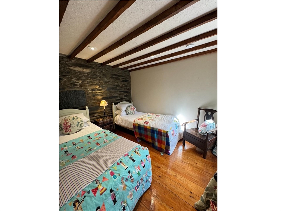 Twin Bedroom at Coedfa Bach with original wooden floor and original wooden mullion window facing the grounds of Coedfa.  Beamed ceiling and feature fi
