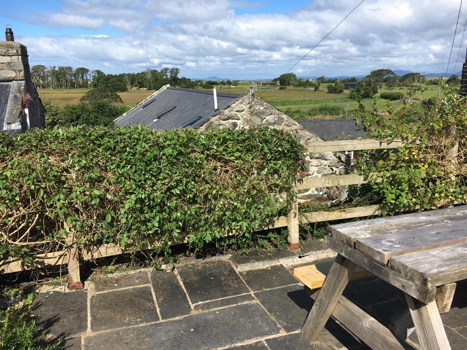 A slate patio in elevated position overlooking the self catering cottages with view out towards the sea and the mountains of the Llŷn peninsula