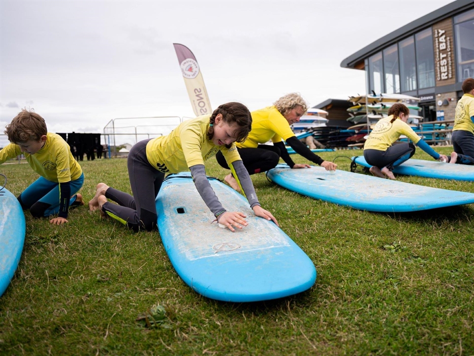 Image of people practicing on surf boards on the grass.