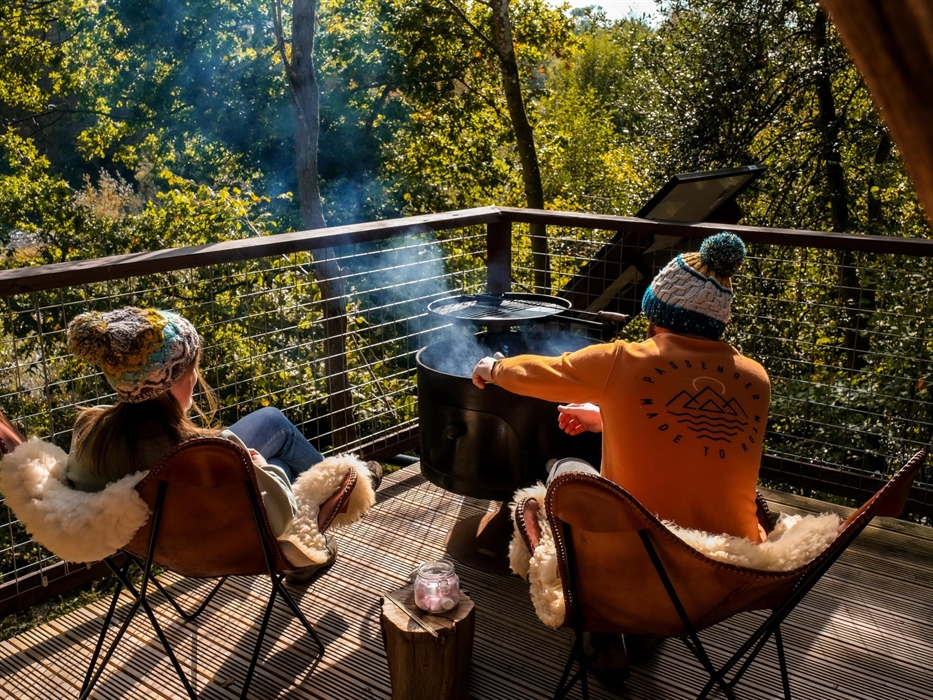 Couple cooking on a firepit on a deck of glamping accommodation at Hay-on-Wye, Wales