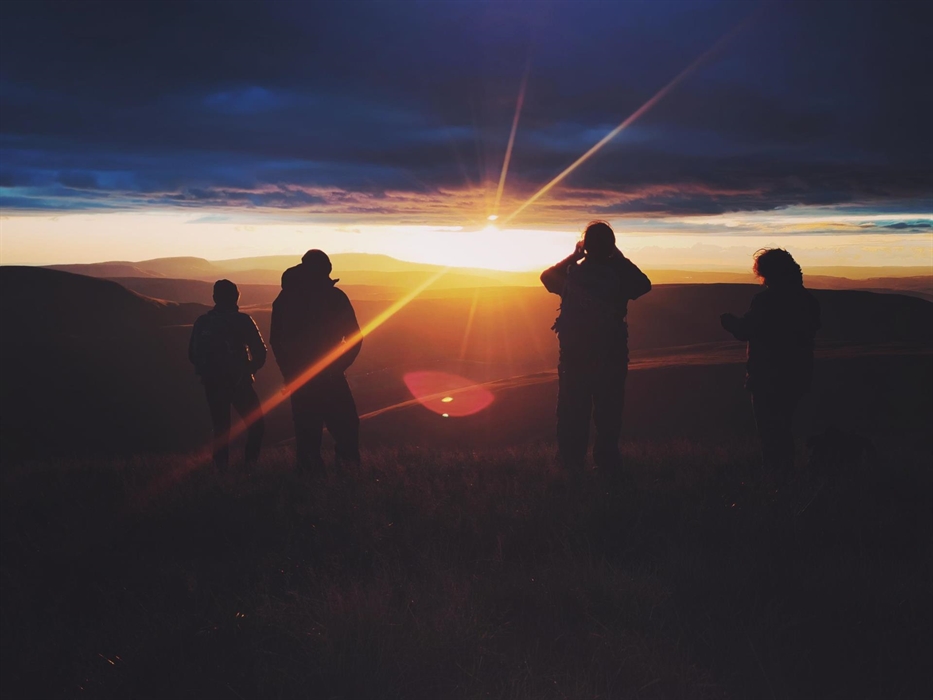 Four people watching the sunset over layers of mountains of the Brecon Beacons