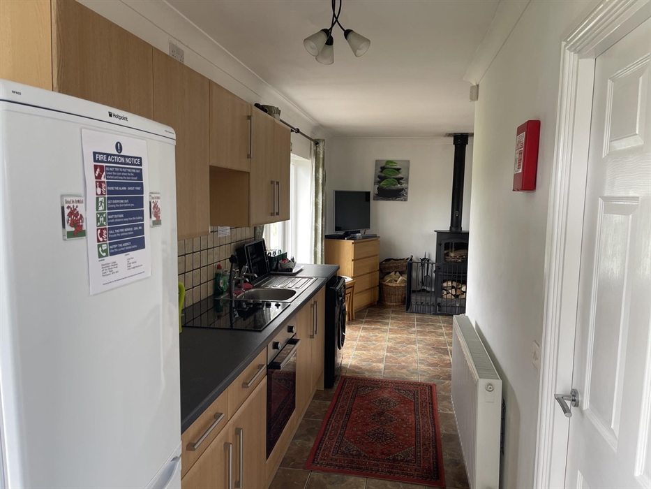 Shows fridge freezer, kitchen wall and base cabinets, ceramic hob, single electric oven, sink, washing machine, radiator and French doors.