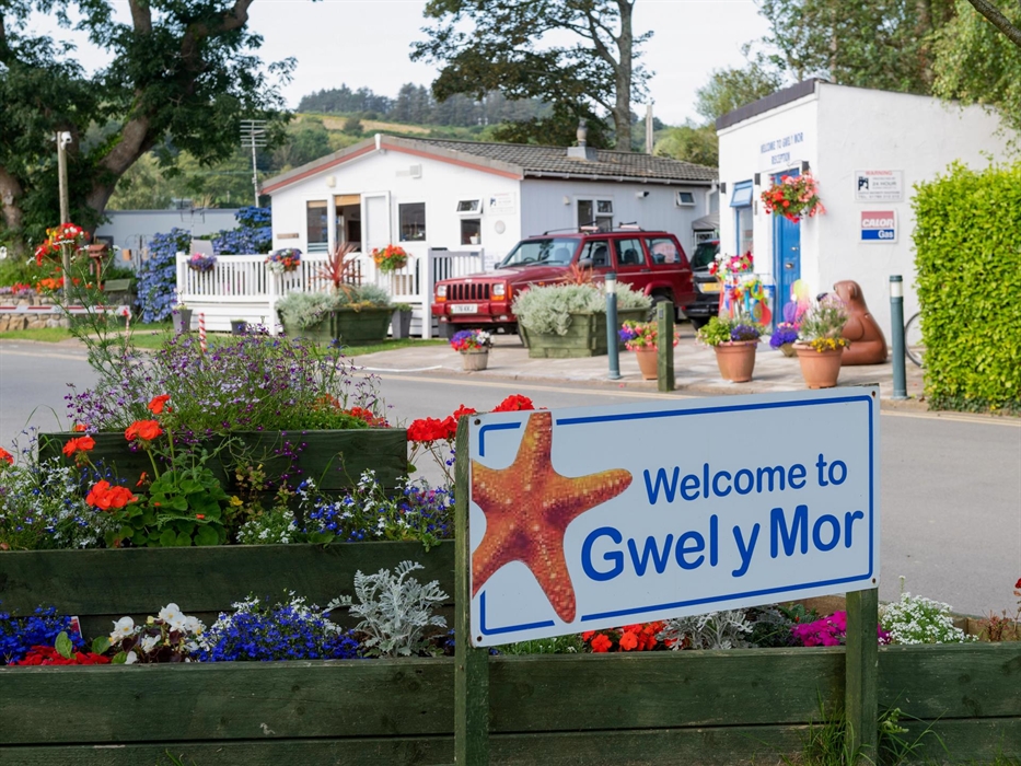 Site entrance showing the site shop, wardens chatel, flowers and welcoming sign