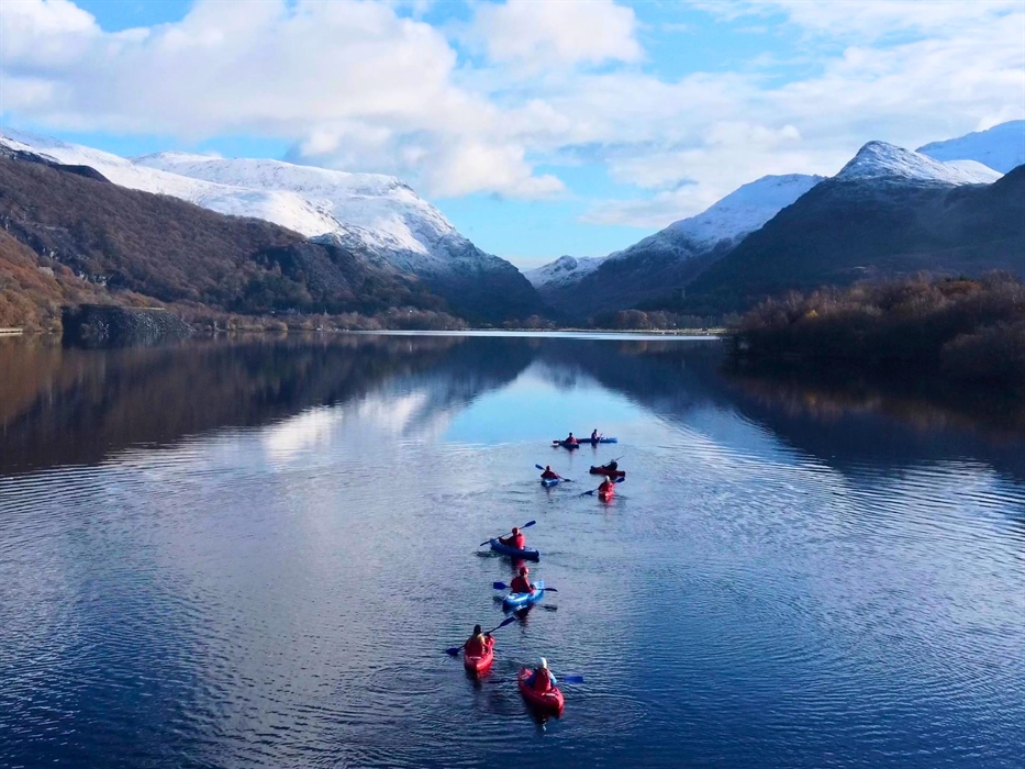 A group of kayakers paddling towards some snowy mountains
