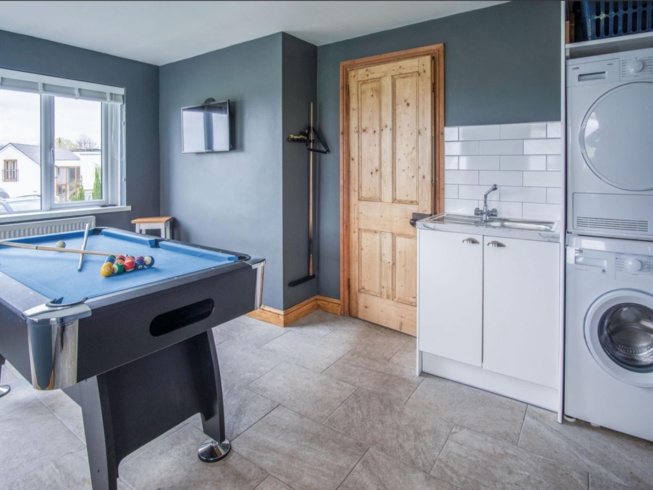 The utility area with washing machine, condensing tumble drier and sink it tacked away in a corner of the games room.