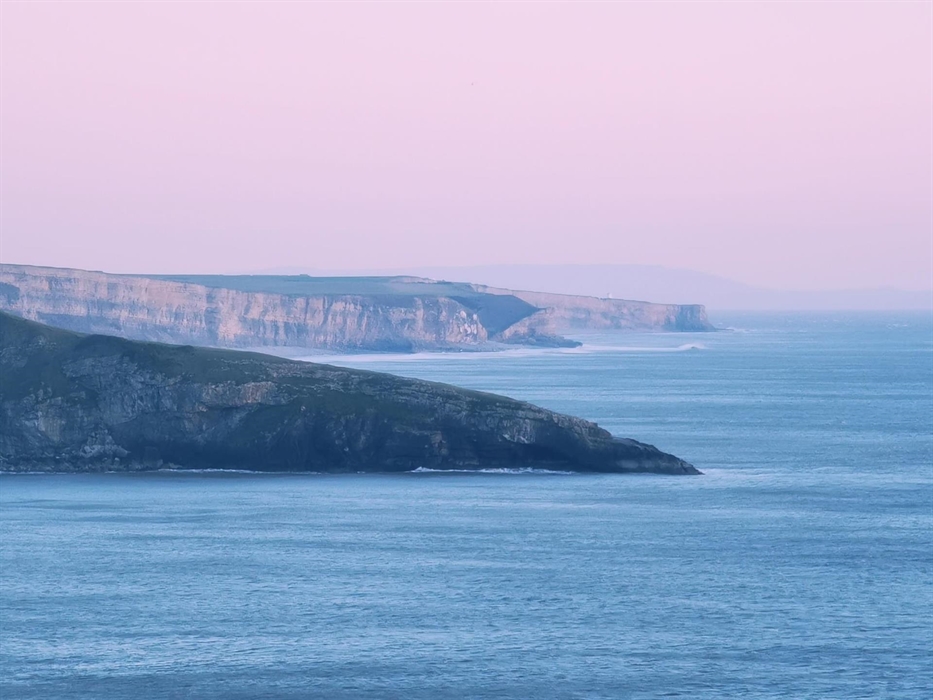 Headlands of cliffs with blue sea and pink sky