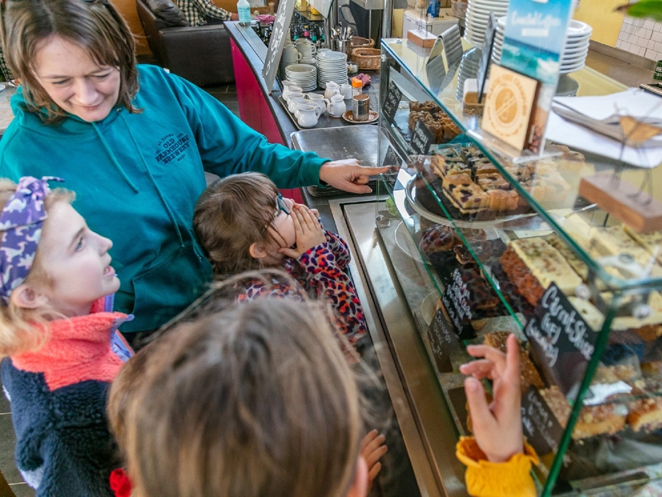 Mother and children looking at cakes on display in cafe