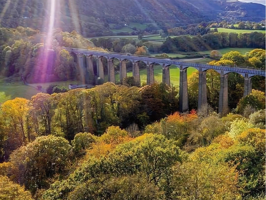 An aerial view of the iconic Pontcysyllte Aqueduct surrounded by Trees and Welsh countryside highlighted beautifully by the sun.
