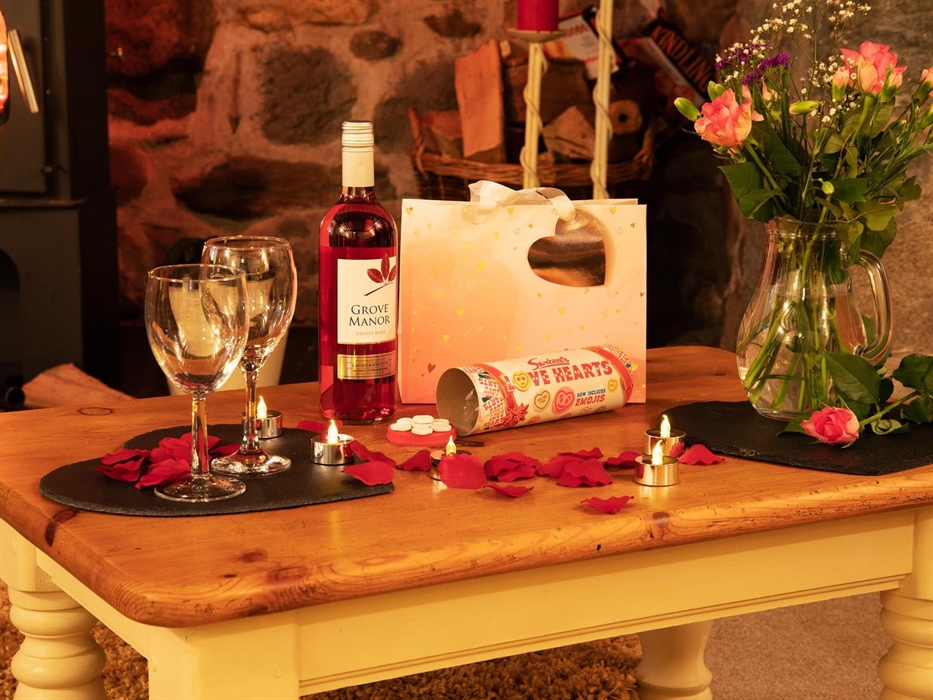 Coffee Table with bottle of wine, wine glasses vase with roses and gift