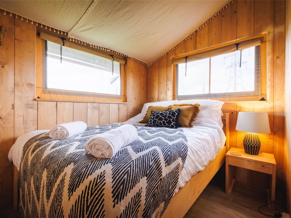 Double bed with giraffe pattern cushion, throw, towels, bedside table and African styled lamp